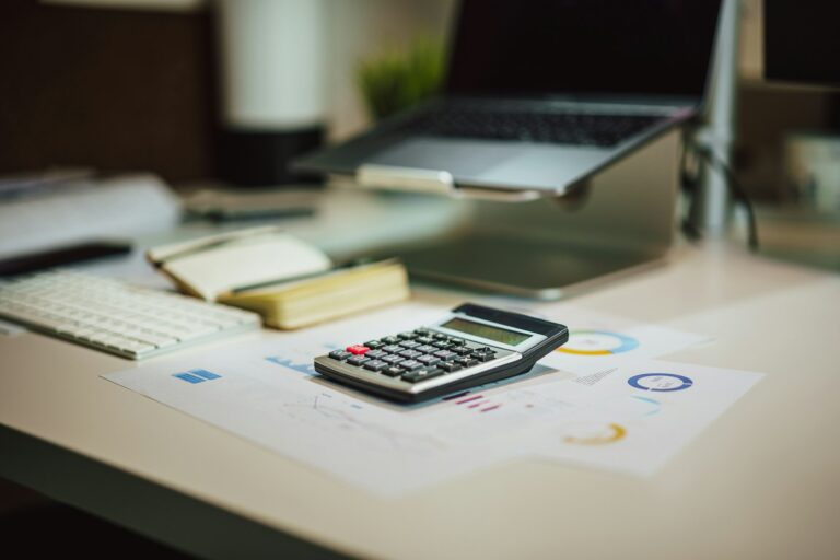 Calculadora sobre mesa ao lado de notebook para cálculos contábeis