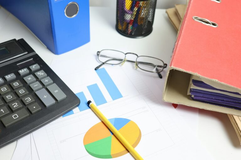 Mesa com calculadora, gráficos e pastas financeiras