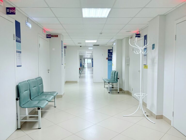 Corredor de hospital com bancos e portas de atendimento