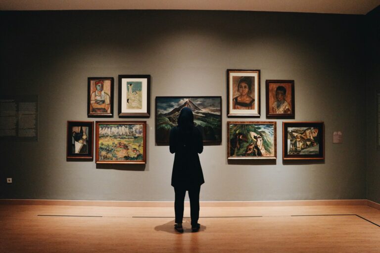 Visitante observando quadros em sala de museu