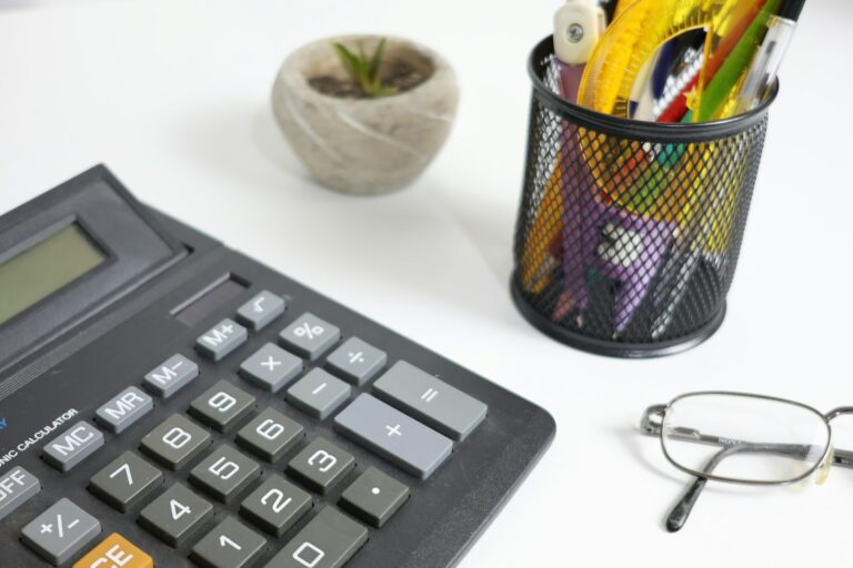 Mesa de trabalho com calculadora, óculos e canetas para elaboração de laudos