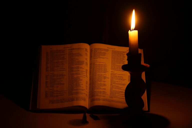 Bíblia aberta iluminada pela luz de uma vela